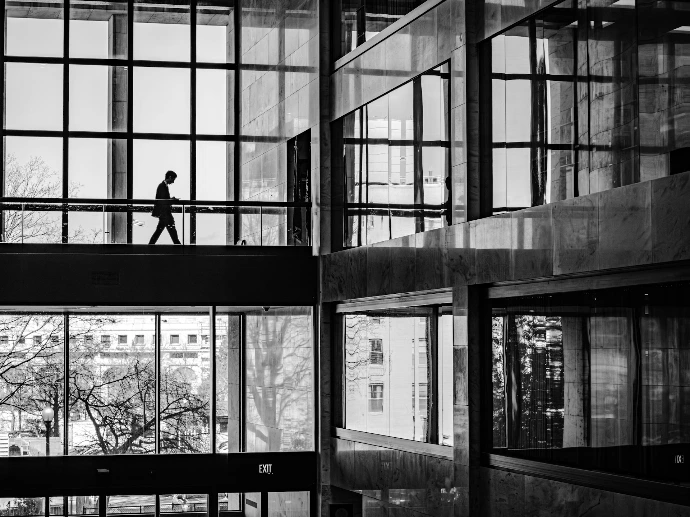 A person walks on a walkway inside a modern building.